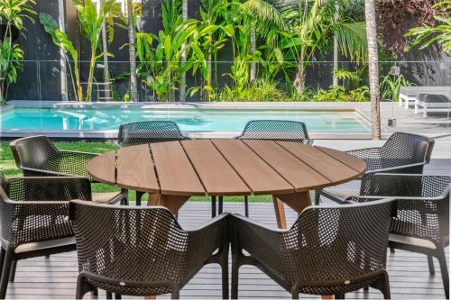 a wooden table and chairs in front of a pool at Lady Luxe - Beautiful spacious pet friendly home near the ocean in Byron Bay