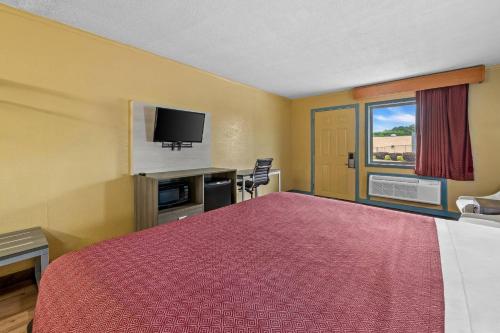 a hotel room with a bed and a flat screen tv at Econo Lodge Charlotte Airport Area in Charlotte