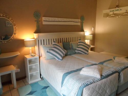 a bedroom with a bed with pillows and a mirror at A Cherry Lane Self Catering and B&B in Bloemfontein