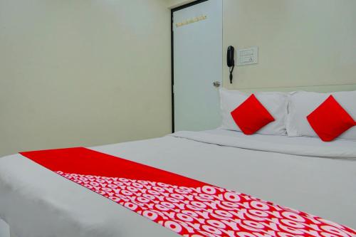 a white bed with red sheets and red pillows at Super Hotel O Happy Homely Stay in Pune