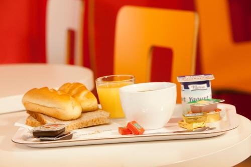 a plate of food with bread and a glass of orange juice at Premiere Classe Quimper in Quimper