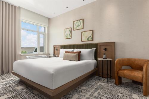 a bedroom with a large white bed and a chair at Hotel Railwayparc Montreal, Tapestry Collection By Hilton in Montréal