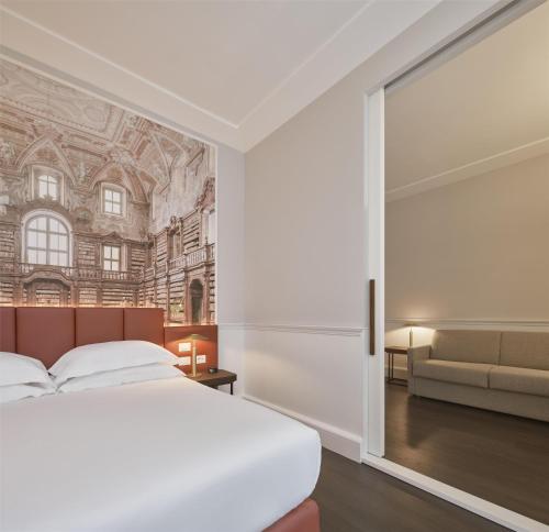 那不勒斯Palazzo Caracciolo Naples的带床和沙发的卧室