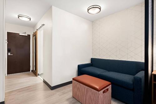 a living room with a blue couch and a stool at Everhome Suites Huntsville - Research Park in Huntsville