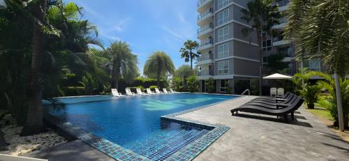 a swimming pool with chairs and a building at Whale Marina Condominium in Na Jomtien