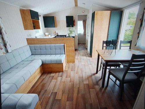 a living room with a couch and a table and a kitchen at Chalet Meerwijck mit Terrasse am Wasser und Meer mit Schwimmbad in Kropswolde