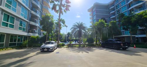 a white car and a truck parked in a parking lot at Whale Marina Condominium in Na Jomtien