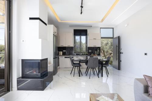 a living room with a fireplace and a table and chairs at Villa Me - With Private Pool in Roumelí