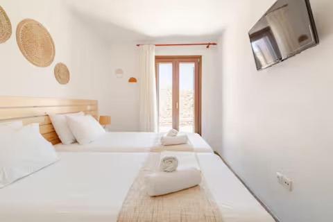 a white room with two beds and a tv at Marilia VIllage Spathi Kea "Villa Helios" in Spathi 