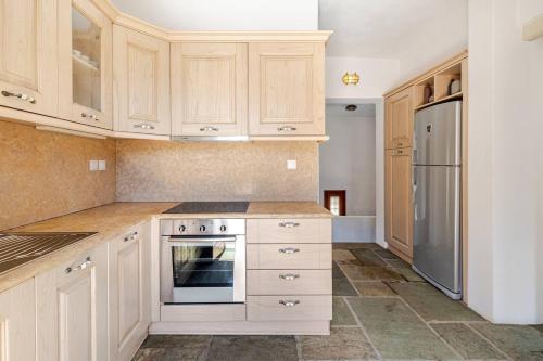 a kitchen with white cabinets and a refrigerator at Marilia VIllage Spathi Kea "Villa Helios" in Spathi 