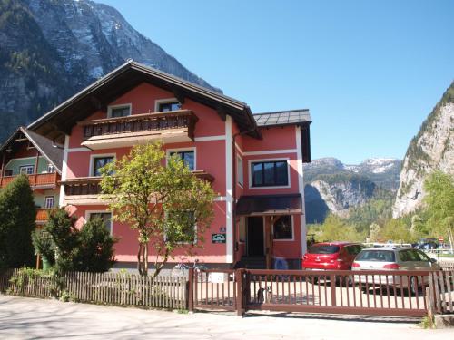 a pink house with mountains in the background at Haus Höll Herta in Hallstatt
