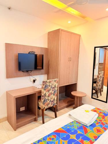 a room with a desk and a tv and a bed at Hotel Melano in Zirakpur