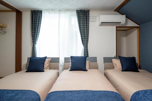 two beds in a room with a window at KAMUI Stay in Asahikawa