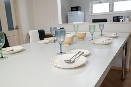 a table with plates and wine glasses on it at KAMUI Stay in Asahikawa