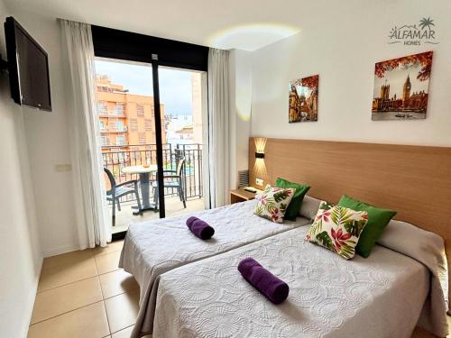 1 dormitorio con 2 camas con almohadas moradas en Sakura Suite - Modern Apartment with Parking & Swimming Pool, en Lloret de Mar