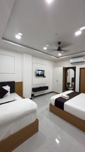 a bedroom with two beds and a flat screen tv at Hotel White Aura in Nāi