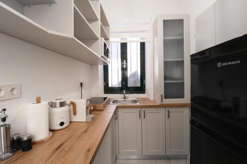 eine Küche mit weißen Schränken und einer Spüle in der Unterkunft Venetian Vicolo by CorfuEscapes in Korfu-Stadt