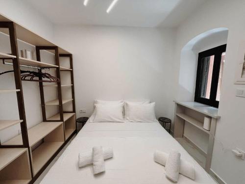 ein Schlafzimmer mit einem Bett mit weißen Laken und Regalen in der Unterkunft Venetian Vicolo by CorfuEscapes in Korfu-Stadt