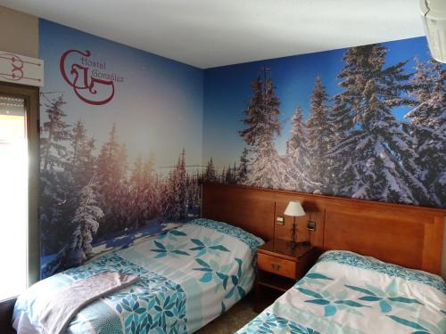 a bedroom with two beds and a mural of trees at Hostal González in Guadarrama