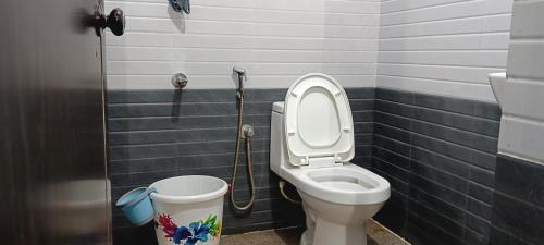 a bathroom with a toilet and a bucket at Royal Valley Apartment in Kalpetta