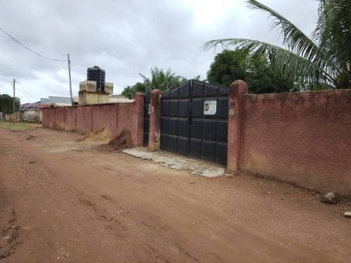 a fence on the side of a dirt road at Quiet and Secure House, Hohoe in Hohoe