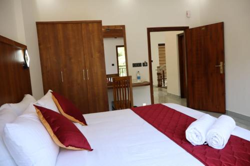 a bedroom with a large bed with red and white pillows at Rhythm Stays in Munnar
