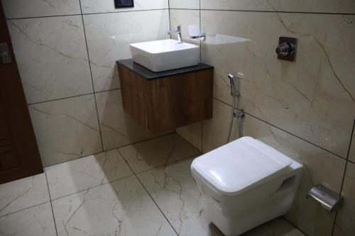 a bathroom with a white toilet and a sink at Rhythm Stays in Munnar