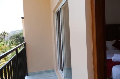 a room with a balcony with a bed and a window at Rhythm Stays in Munnar