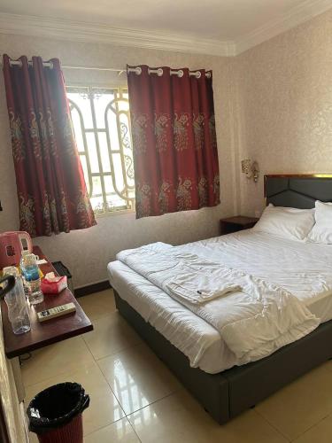 a bedroom with a bed and a window with red curtains at Twilight Inn in Phnom Penh