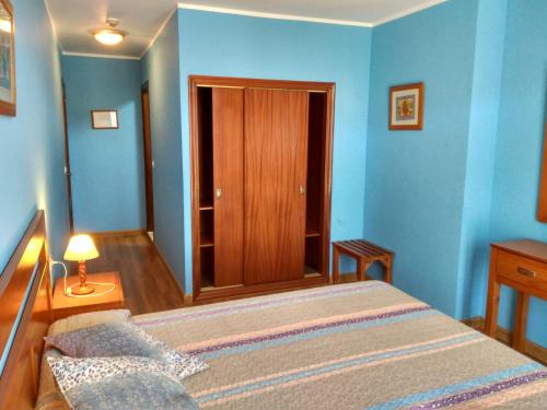 a bedroom with blue walls and a bed and a lamp at Hotel Águila Real in Cangas de Onís