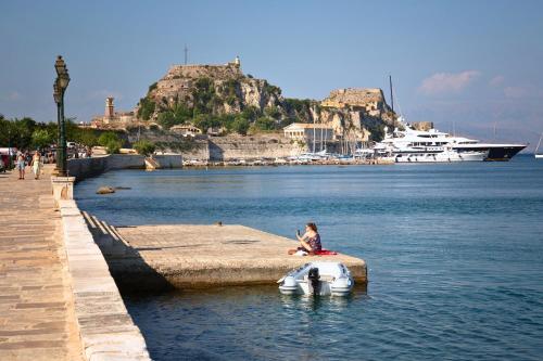a person sitting on a boat in a body of water at CORFU TENNIS Studios in Agios Rokkos