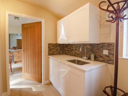 una cucina con mobili bianchi e un lavandino di Apple Tree Cottage a York