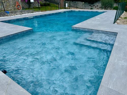 a swimming pool with blue water in a yard at Garda Lake View Pool & Parking in Gardone Riviera