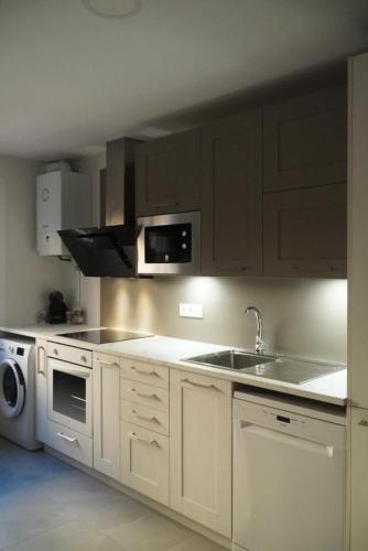 a kitchen with white cabinets and a sink and a microwave at Chalet Avenida El Barraco Avila in El Barraco