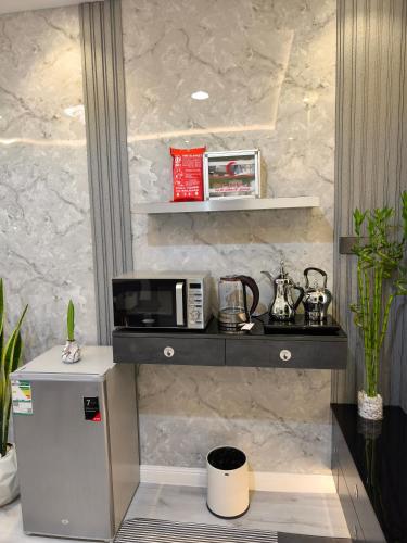 a kitchen with a microwave on a shelf at استديو بسمة الضيافة in Unayzah