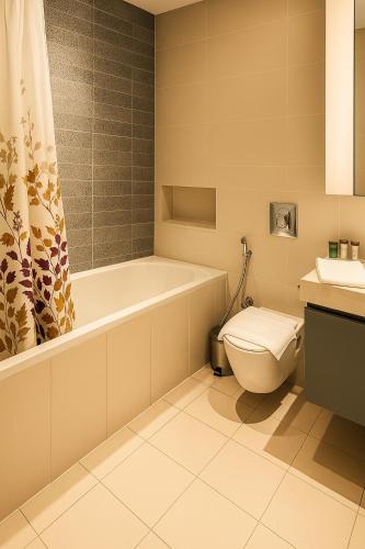 a bathroom with a tub and a toilet and a sink at Best Emaar Beachfront view one bedroom in Dubai