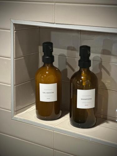 two bottles of alcohol are sitting on a shelf at La Maison Gervaiserie & Spa in Réville