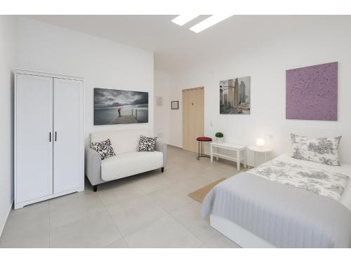 a white bedroom with a bed and a couch at Fantastico 4 - with large private terrace, free parking, air conditioning, BBQ in Puerto de la Cruz