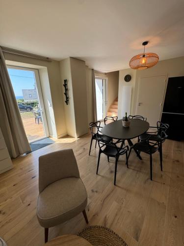 - un salon avec une table, des chaises et une chaise dans l'établissement Maison rénovée vue mer, à Plouhinec