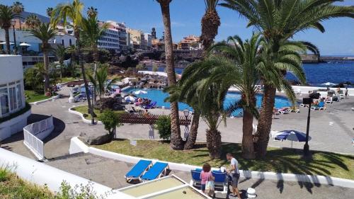 a view of a resort with a pool and palm trees at Fantastico 4 - with large private terrace, free parking, air conditioning, BBQ in Puerto de la Cruz