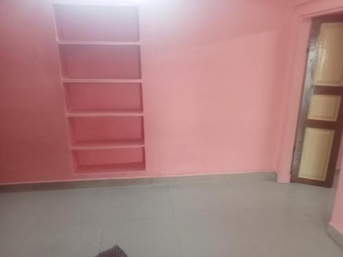 ティルヴァンナーマライにあるSarathy Houseのピンクの壁と空の棚のある部屋
