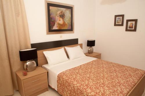 a bedroom with a bed and two night stands with lamps at Palmira Apartments in Makry Gialos