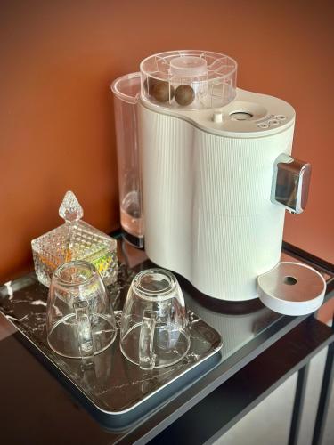 a tray with glasses and a toaster on a table at La Maison Gervaiserie & Spa in Réville