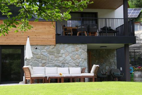 a patio with white couches and chairs on a house at Apart Bieles NEU - Bergoase mit privater Outdoor-Sauna & Massagepraxis in Kauns