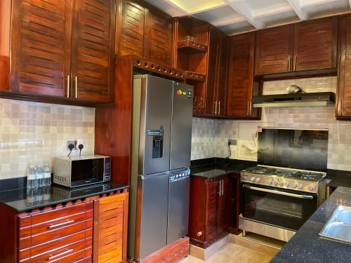 a kitchen with wooden cabinets and a stainless steel refrigerator at A Modern Fully Furnished 5Bedroom House In Rubaga Kampala For Rent in Kampala