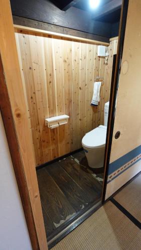 a bathroom with a toilet and a wooden wall at Kashiwaya Inn in Nagiso
