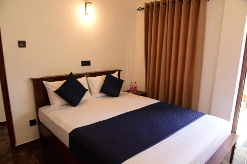 a bedroom with a bed with blue and white pillows at The Kingfisher Hikkaduwa in Hikkaduwa