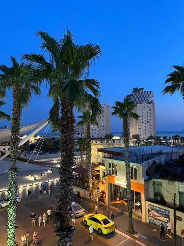 a street with palm trees and a yellow taxi at Hotel Veliera in Durrës