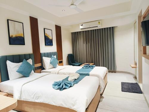 two beds in a hotel room with blue pillows at Hotel Comfort in Surat