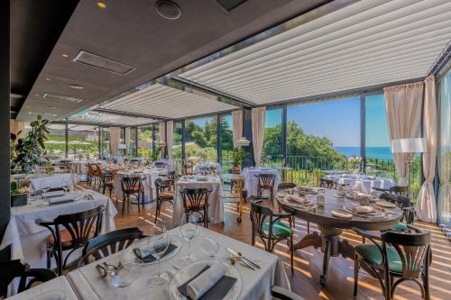 a restaurant with tables and chairs and large windows at Deville & Spa in Costermano sul Garda
